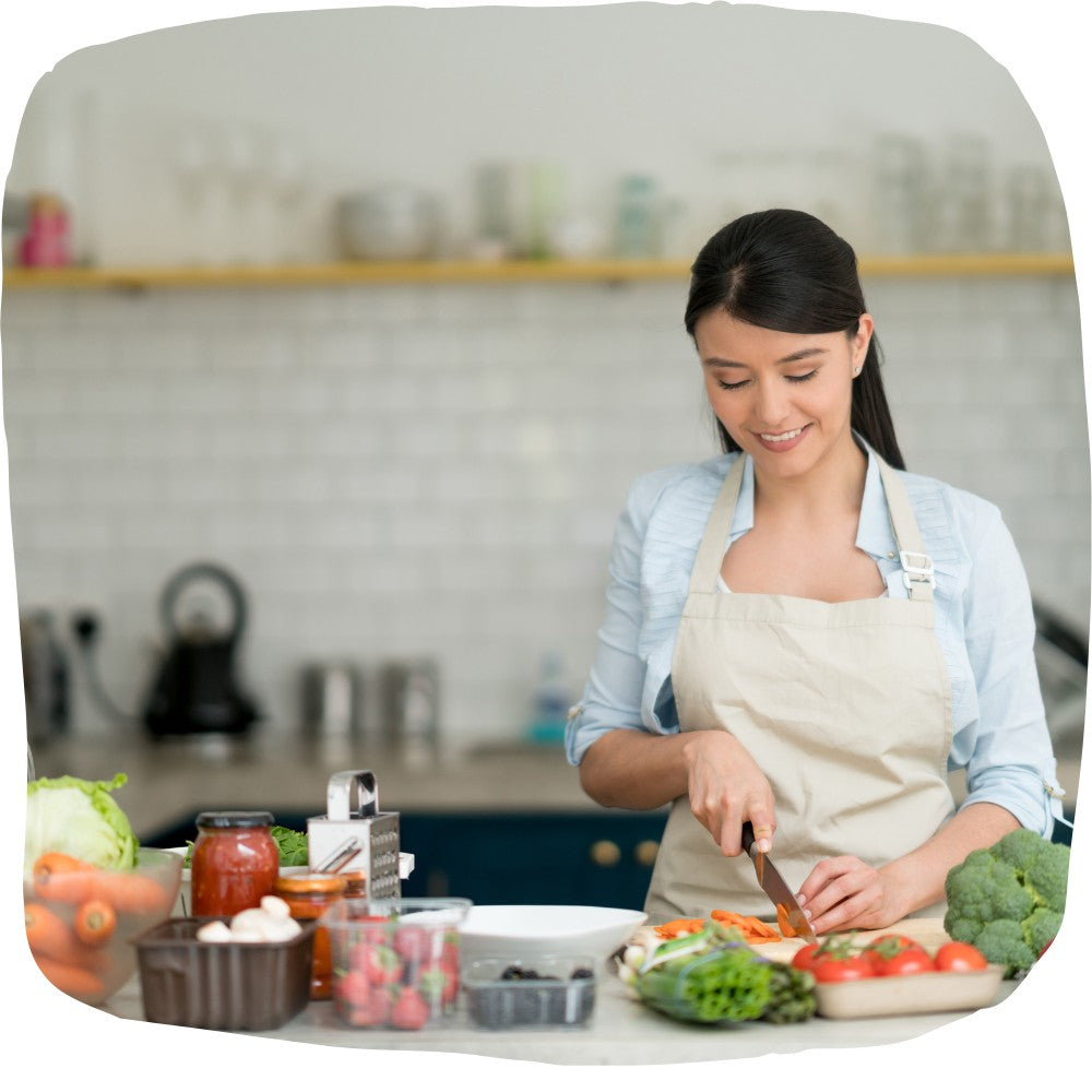 Frau in Küche die Gemüse schneidet und essen zubereitet, lächelnd