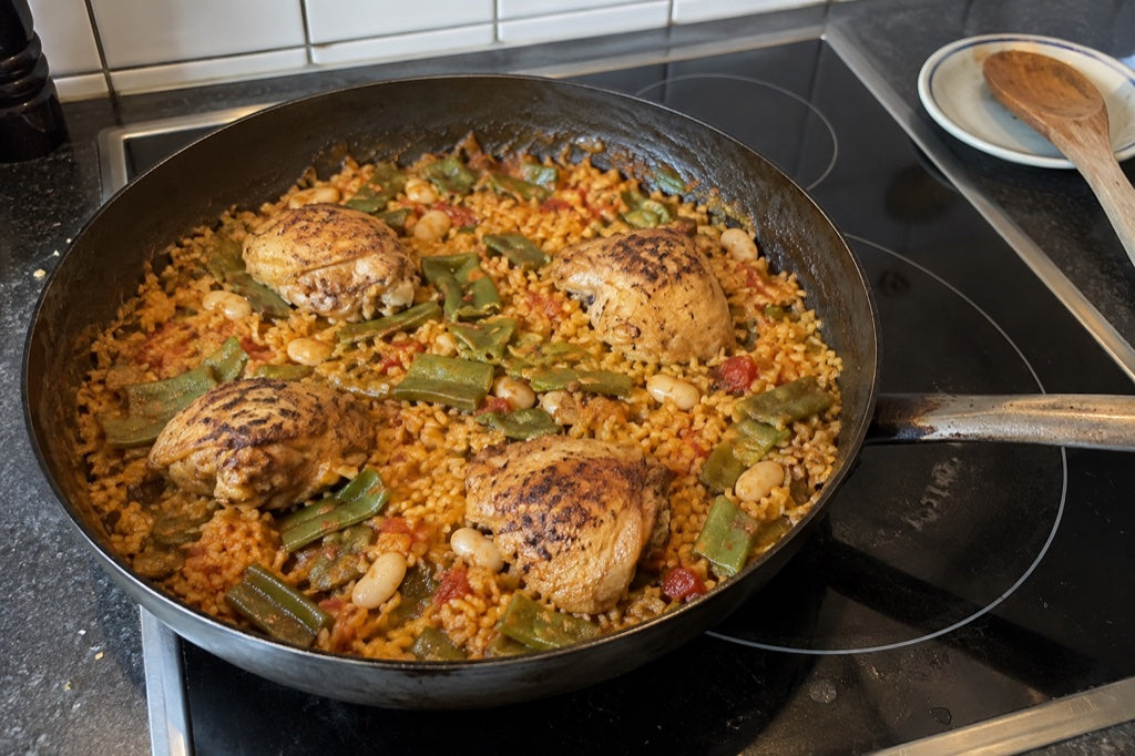 Paella mit Hähnchen und Bohnen auf einem heimischen Ceranfeld